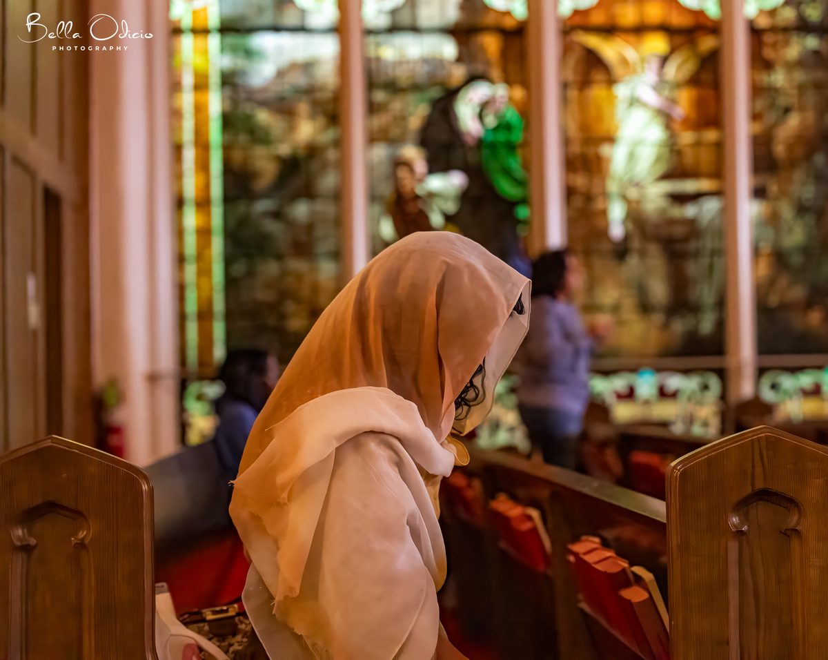 A woman in a head covering praying in the sanctuary